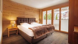 Una camera da letto con una testiera in legno, un letto grande con lenzuola bianche, una coperta marrone soffice e un comodino con una lampada.