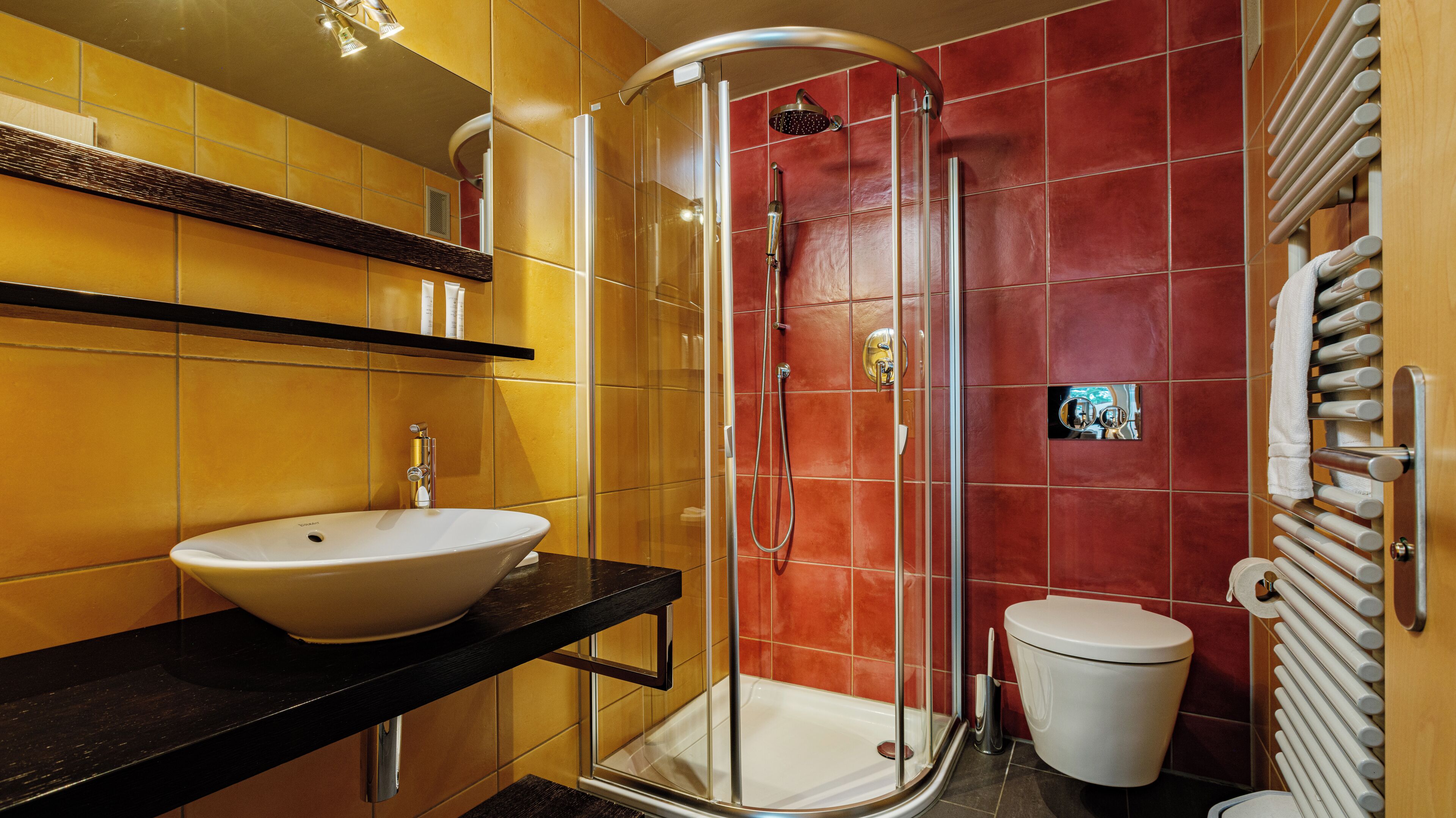 Un baño con un lavamanos blanco, una ducha con cerramiento de vidrio y un inodoro.