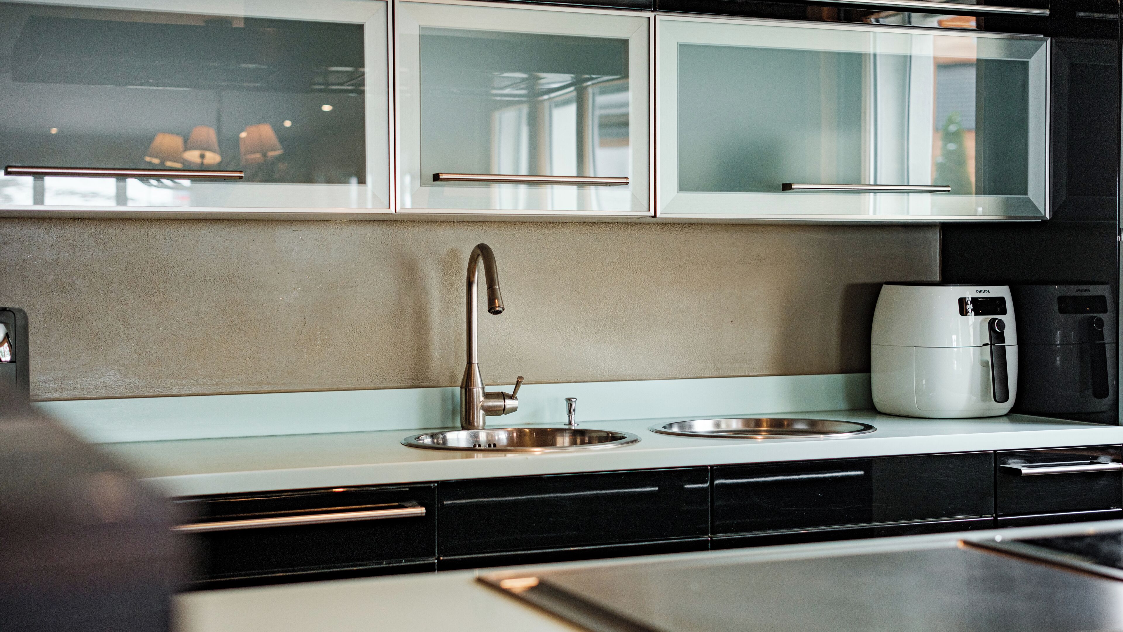Una cocina moderna con un lavamanos de acero inoxidable, una cafetera y un microondas.
