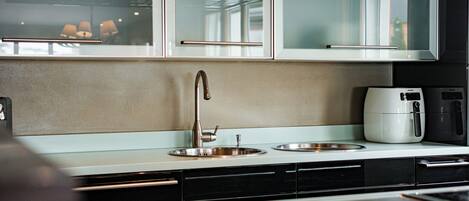 Una cocina moderna con un lavamanos de acero inoxidable, una cafetera y un microondas.