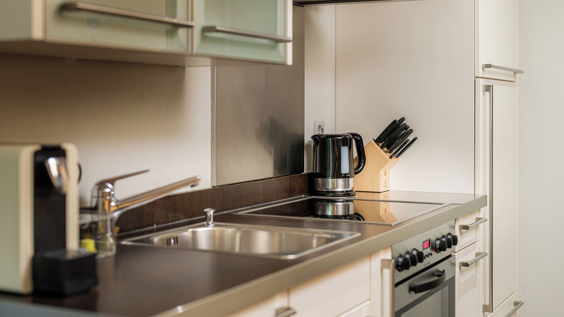 Una cocina moderna con electrodomésticos de acero inoxidable, una cafetera y un bloque de cuchillos.