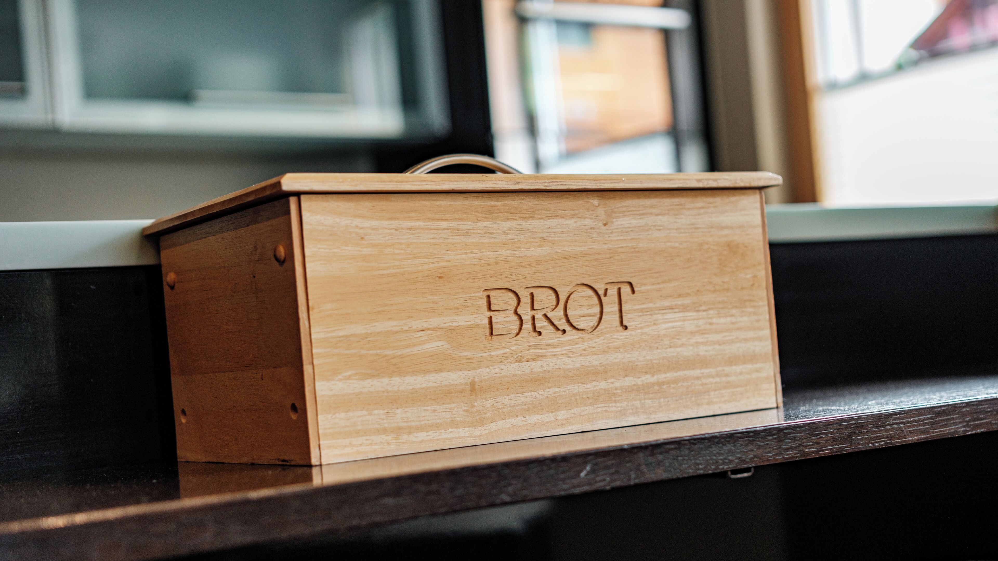 Una caja de madera con la palabra "BROT" grabada, sobre una superficie oscura.