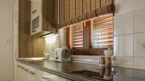 Una cocina moderna con horno empotrado, tostadora y ventana con persianas.
