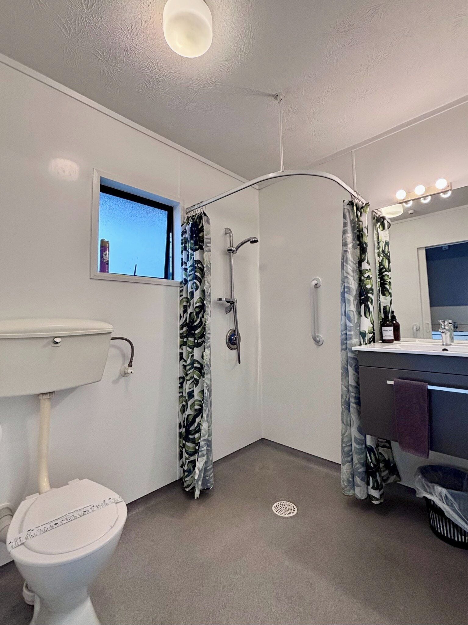Un baño con inodoro, ducha, lavamanos y tocador.