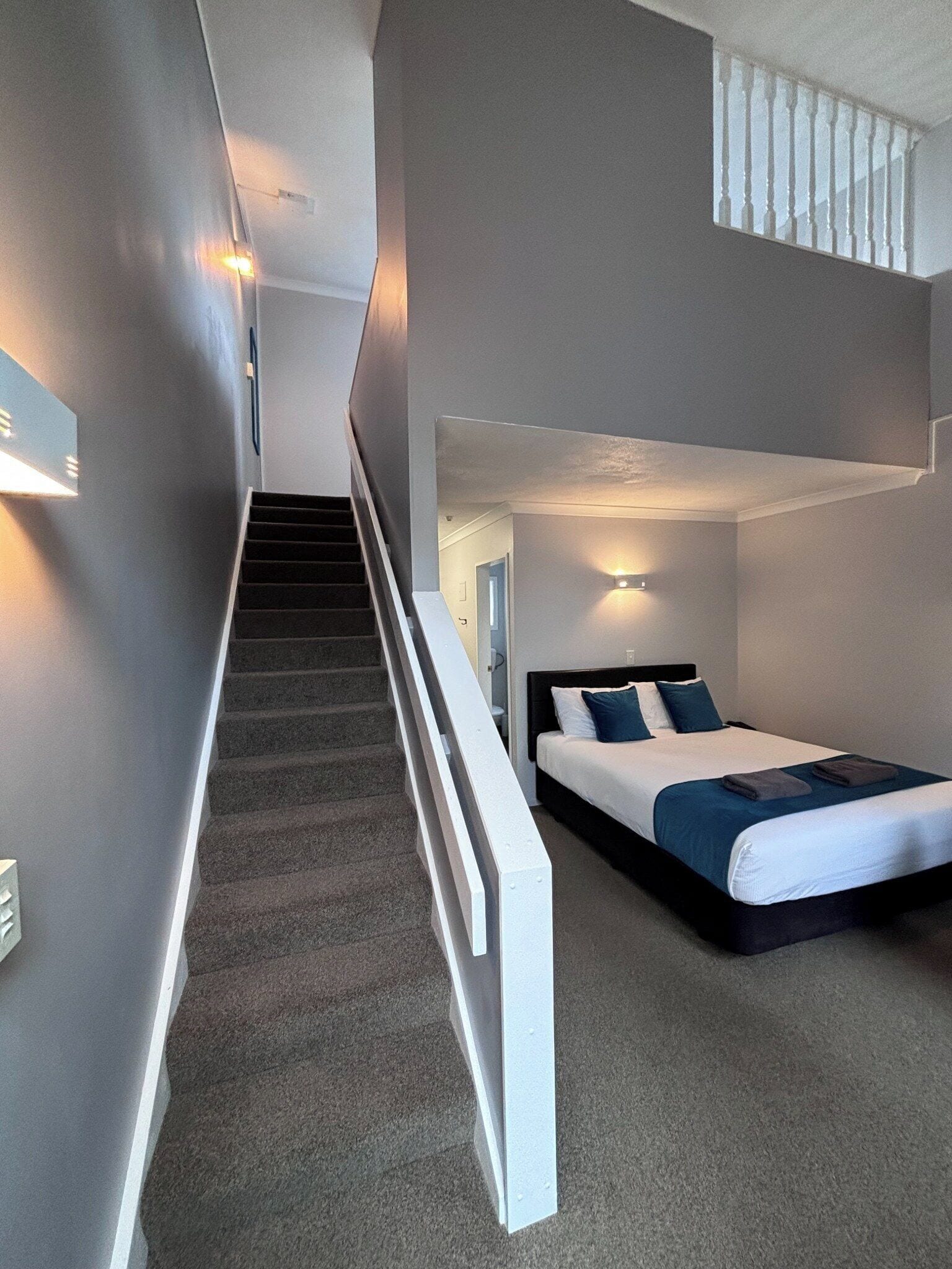 A modern hotel room with a staircase leading to a loft area.