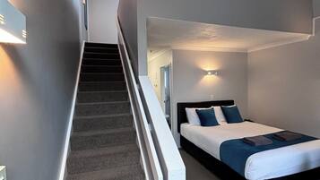 A modern hotel room with a staircase leading to a loft area.
