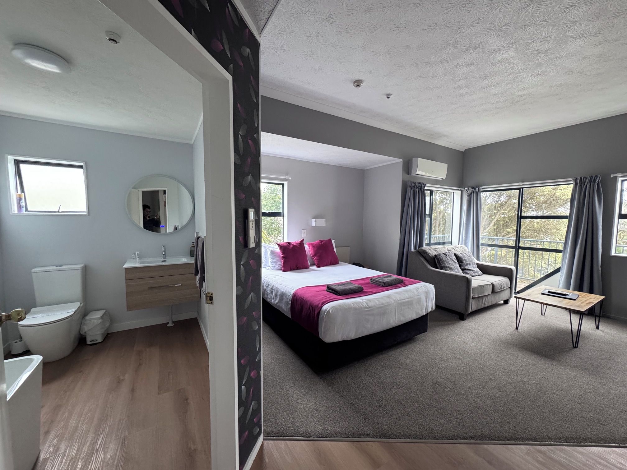 Un dormitorio moderno con una cama, un sofá y una mesita.
