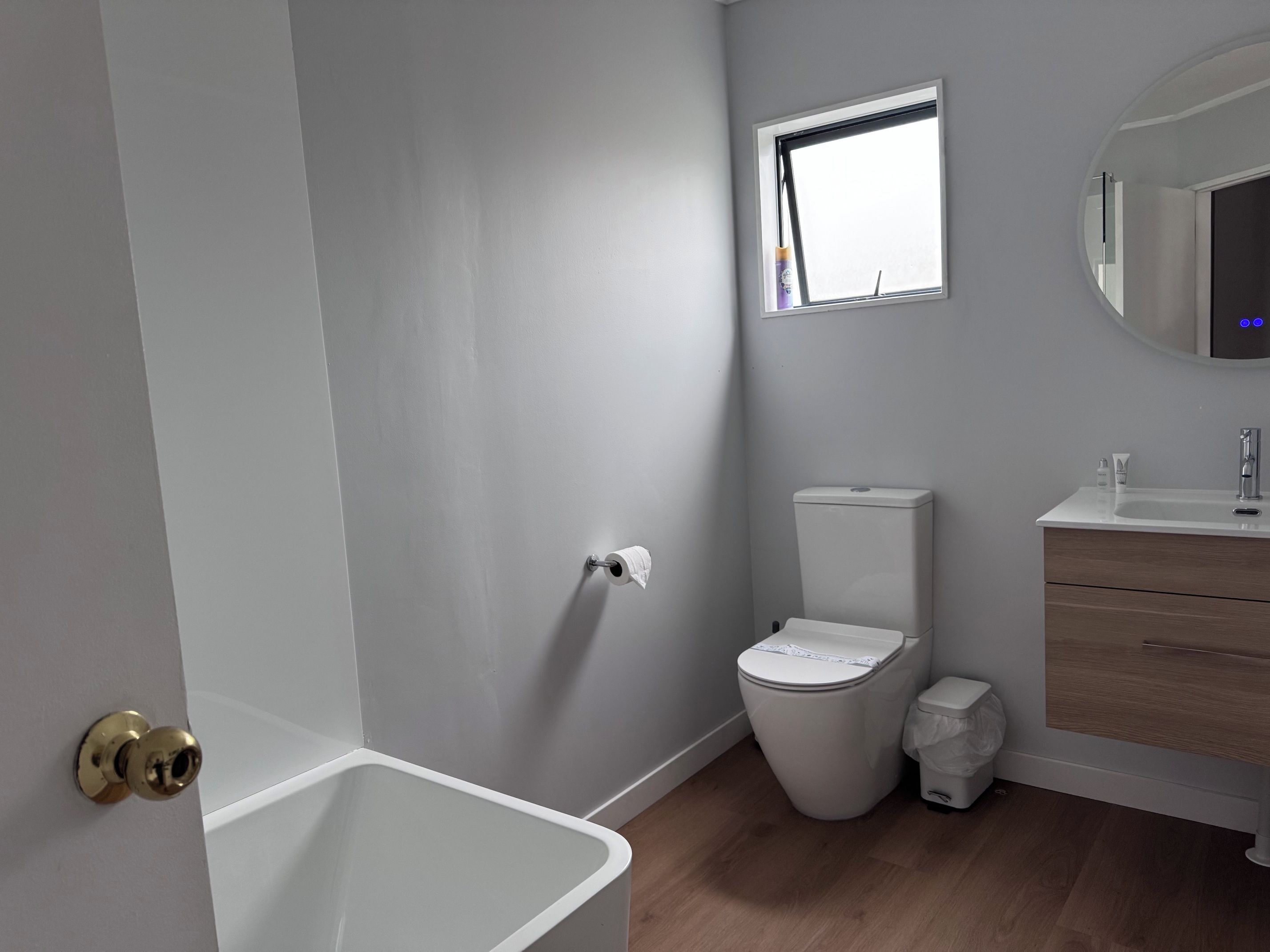A bathroom with a toilet, a sink, a mirror, and a window.