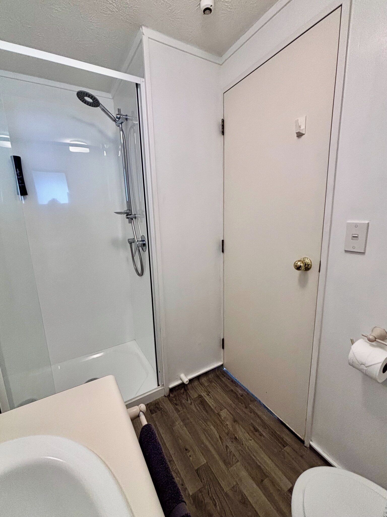 Un baño con cabina de ducha de vidrio, inodoro y lavabo.