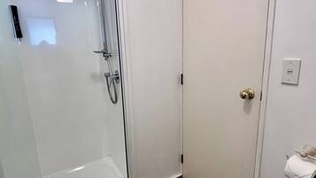 Une salle de bain avec une douche à parois de verre, des toilettes et un lavabo.