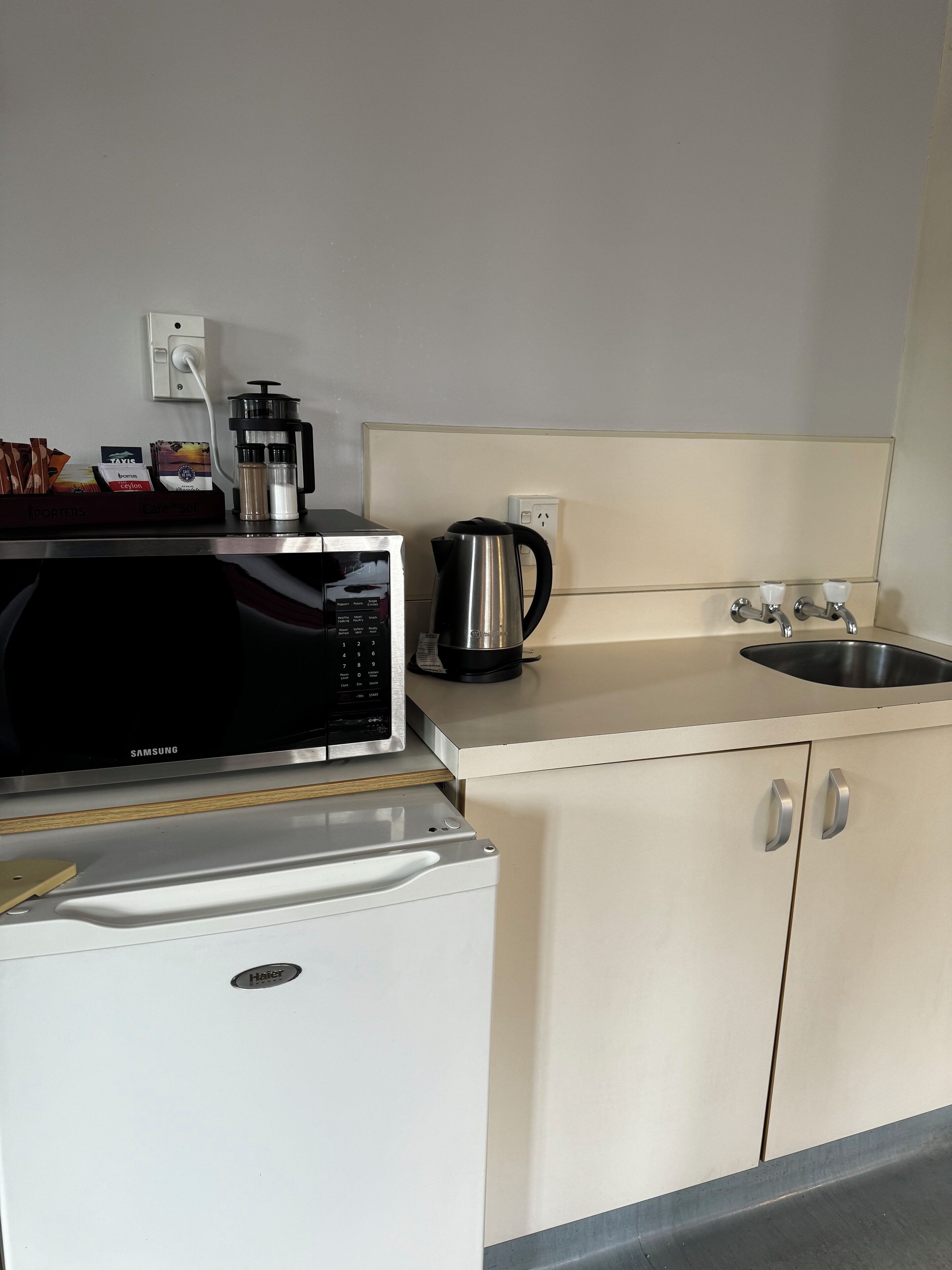 A compact kitchenette with a microwave, coffee maker, and a small refrigerator.