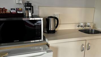 A compact kitchenette with a microwave, coffee maker, and a small refrigerator.