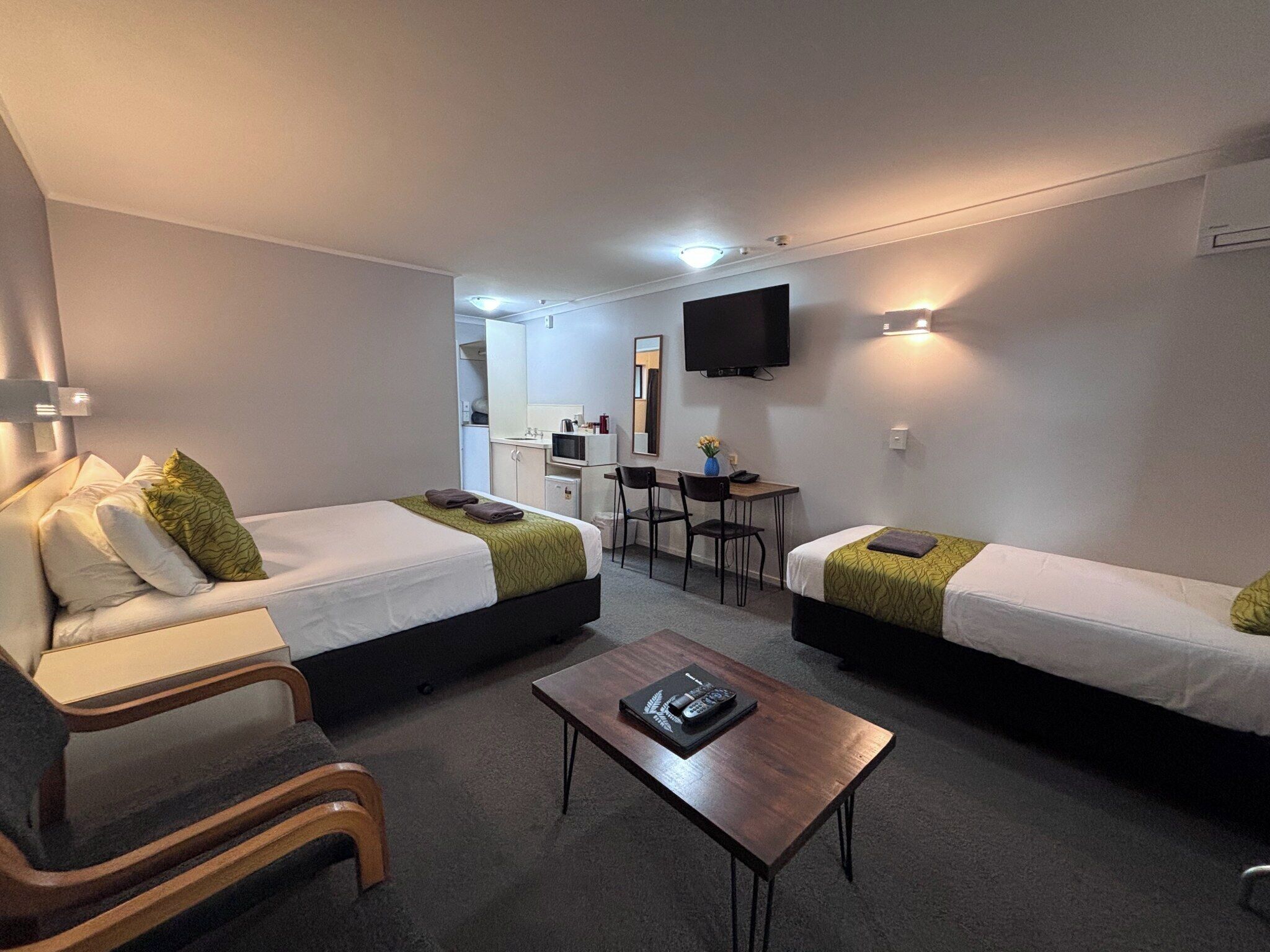 Camera d'albergo con due letti singoli, una piccola scrivania, una sedia, una televisione e un tavolino.
