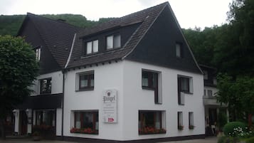 A two-story building with a white facade and dark roof, featuring multiple windows and flower boxes.