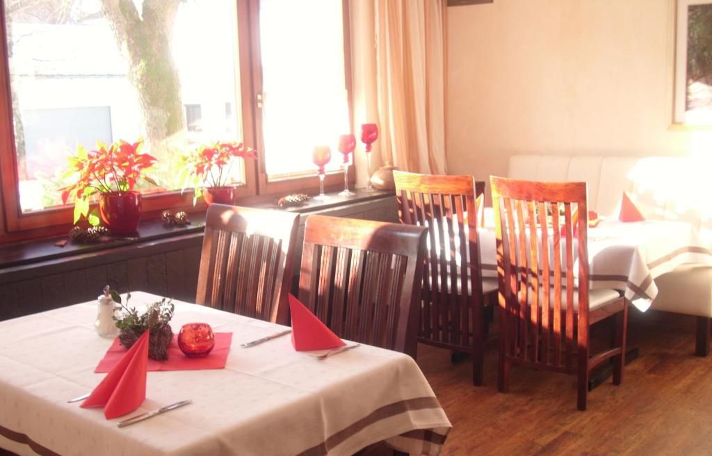 A dining area with a table set for two, wooden chairs, a window with curtains, and a view of the street outside.
