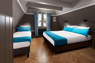 Une chambre avec deux lits, une fenêtre avec des rideaux et un radiateur.