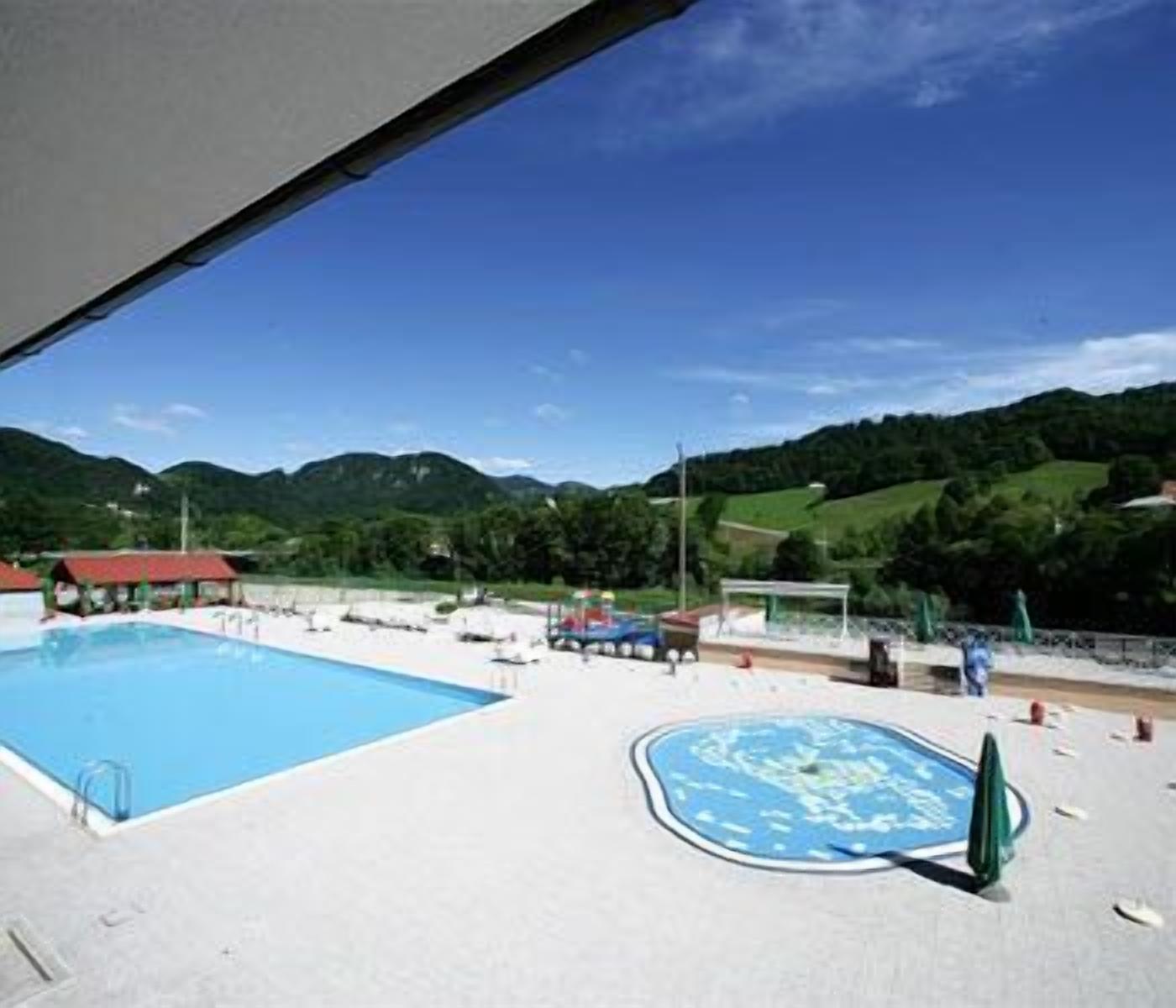 Una piscina con vistas a colinas verdes al fondo.