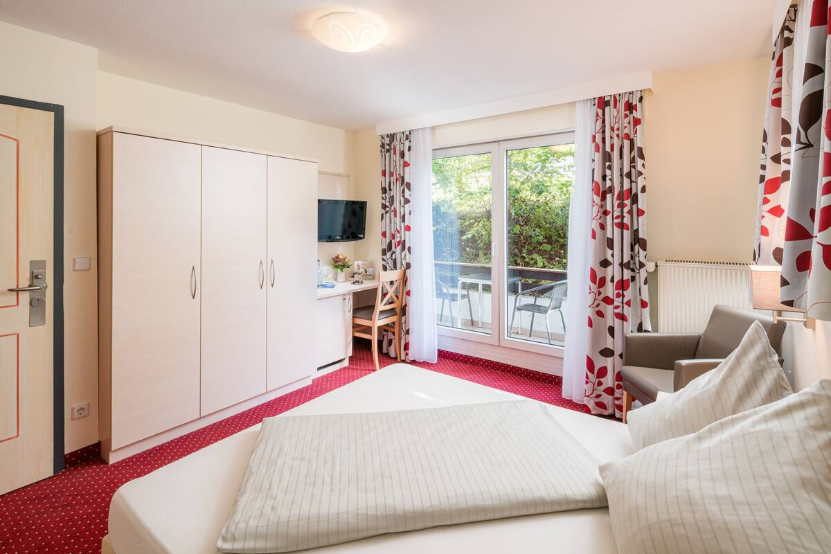 Une chambre d’hôtel avec un grand lit, un bureau, une chaise et un téléviseur.
