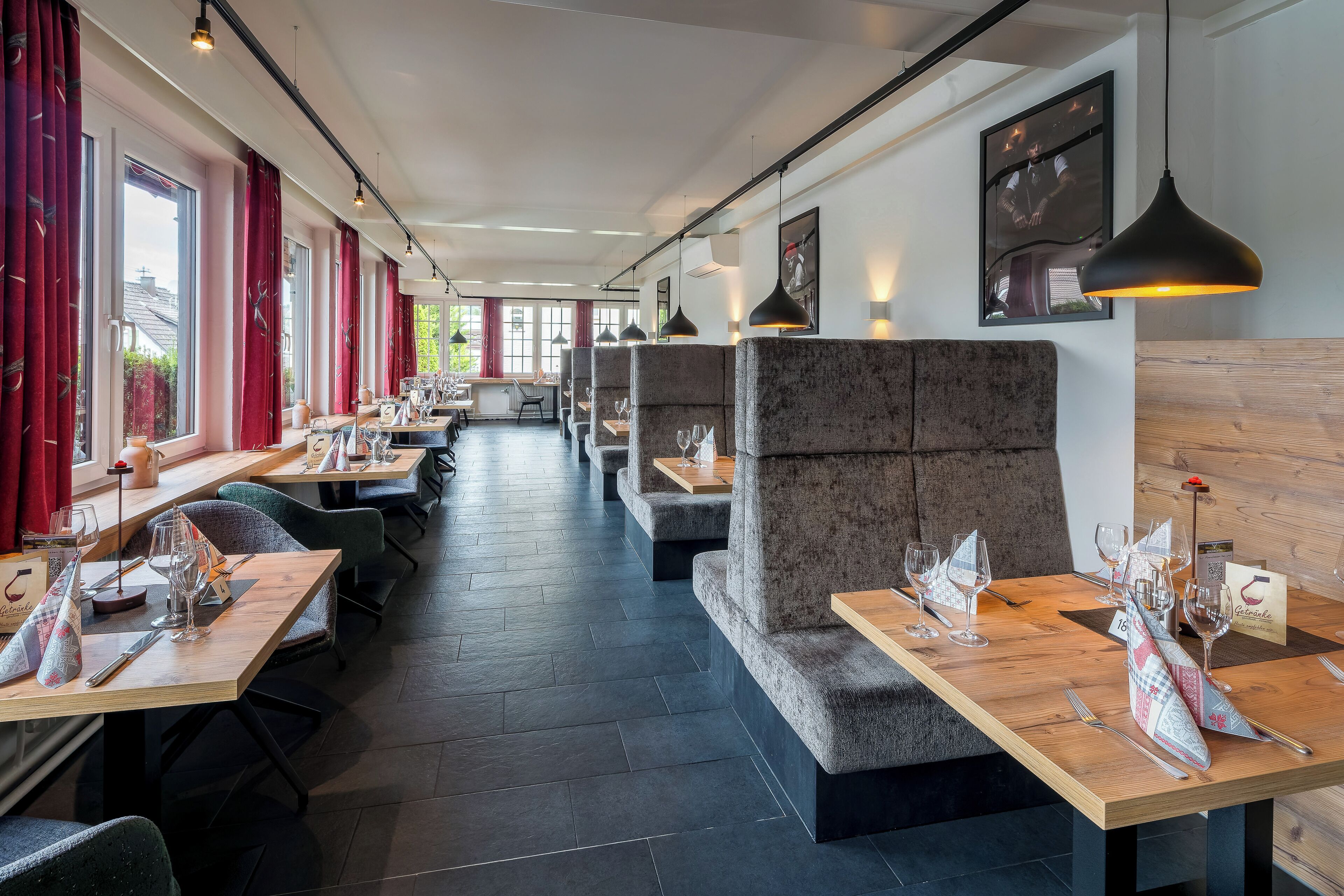 Een restaurant met hoge tafels, comfortabele zitjes en hanglampen.
