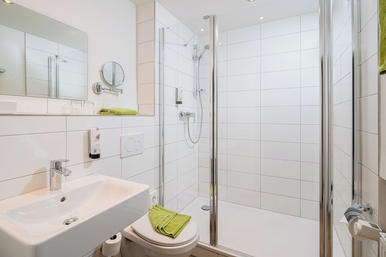 A modern bathroom with a glass-enclosed shower, a white sink, and a toilet.