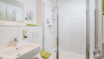 Un baño moderno con ducha de vidrio, lavabo blanco y retrete.