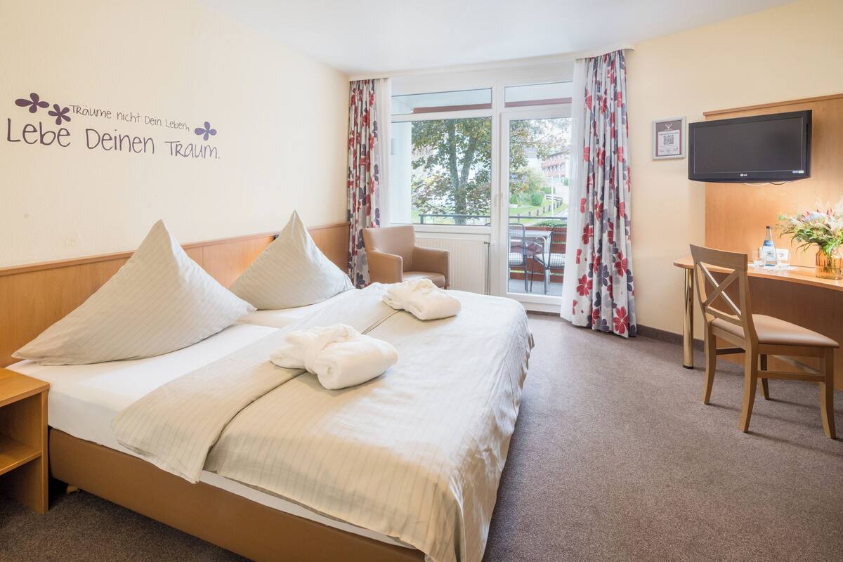 Une chambre d’hôtel avec un lit, un bureau, une chaise et un téléviseur.