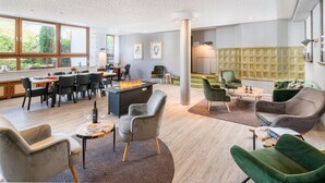 Un salon moderne doté d’une cheminée, de sièges confortables et de grandes fenêtres offrant une vue sur l’extérieur.