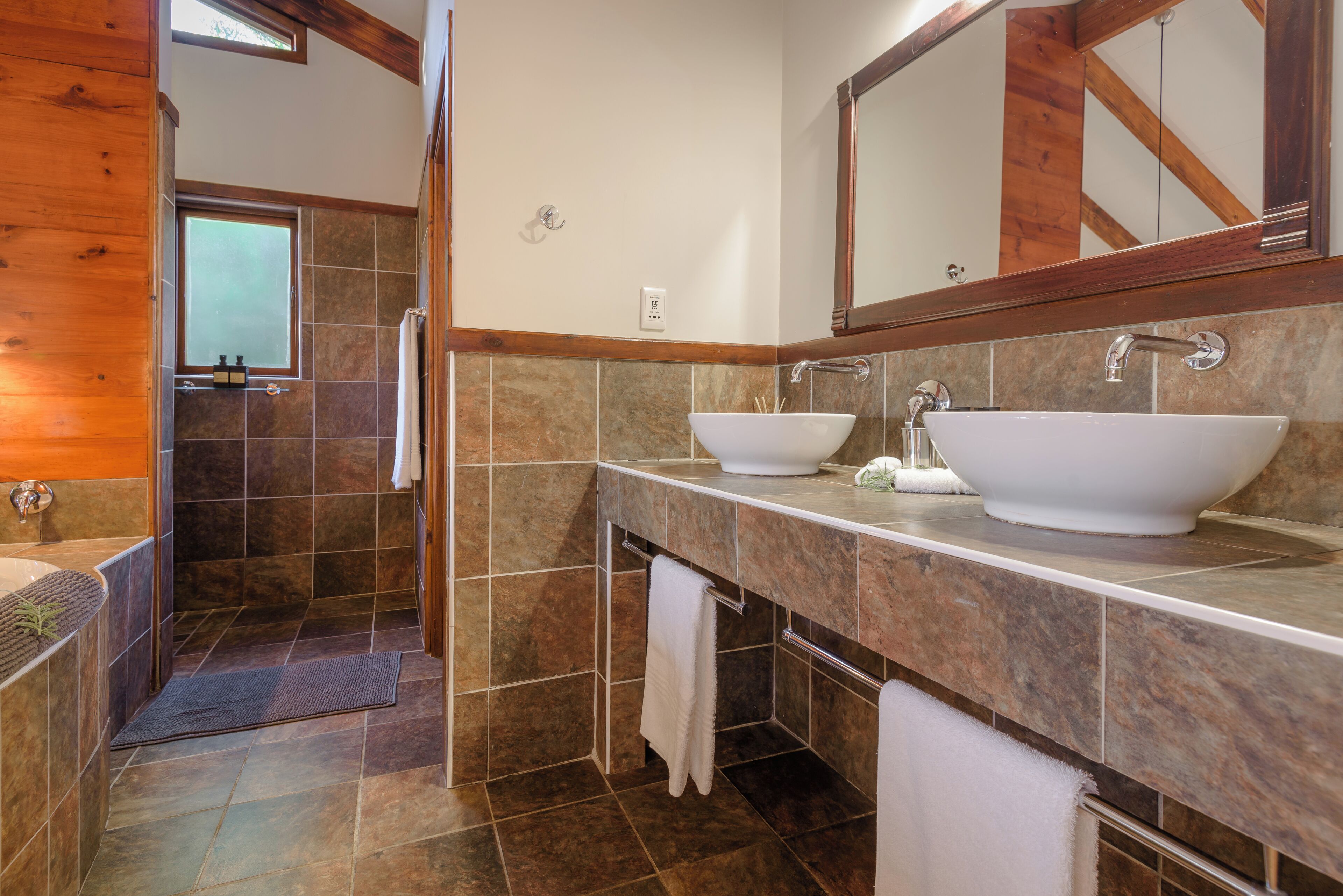 Une salle de bain avec un double lavabo, un grand miroir et un espace douche.