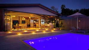 A modern house with an outdoor swimming pool, a covered patio, and a well-lit interior. - Elephant Hide of Knysna Guest Lodge (Knysna)