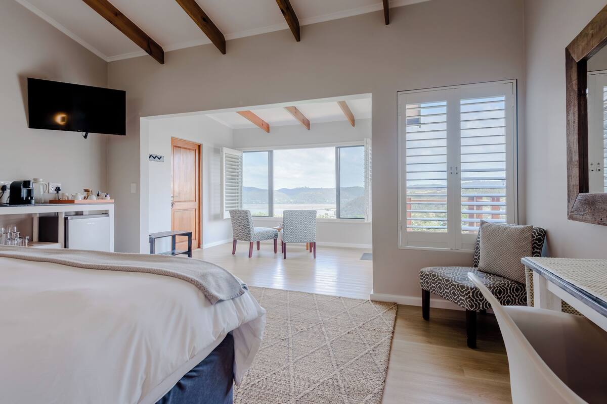 A bedroom with a bed, a desk, a TV, and a view of the outdoors.