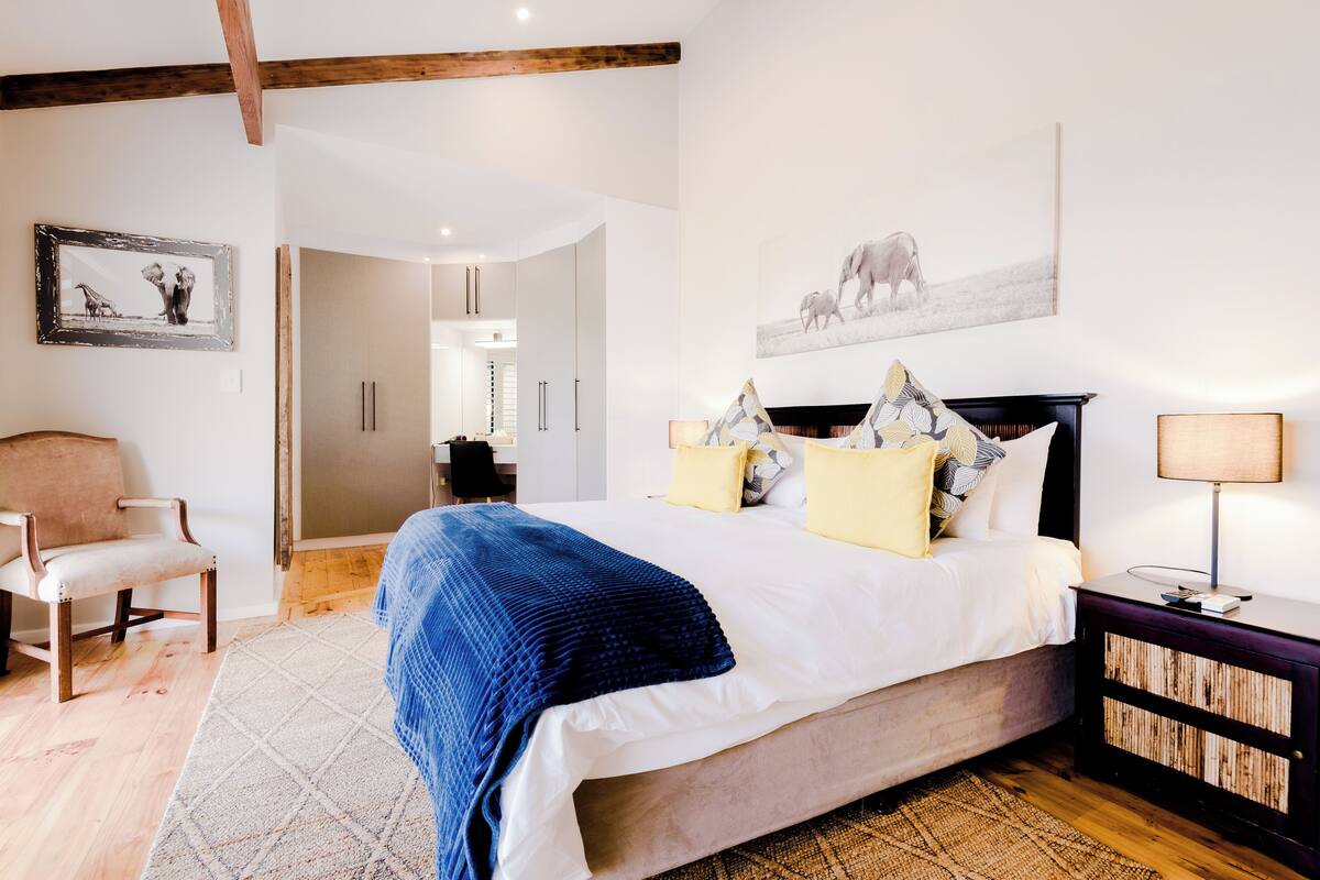 A bedroom with a bed, a chair, a bedside table, and a wall-mounted picture.
