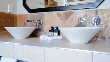 A bathroom with two white vessel sinks, a mirror above, and a towel rack with towels.