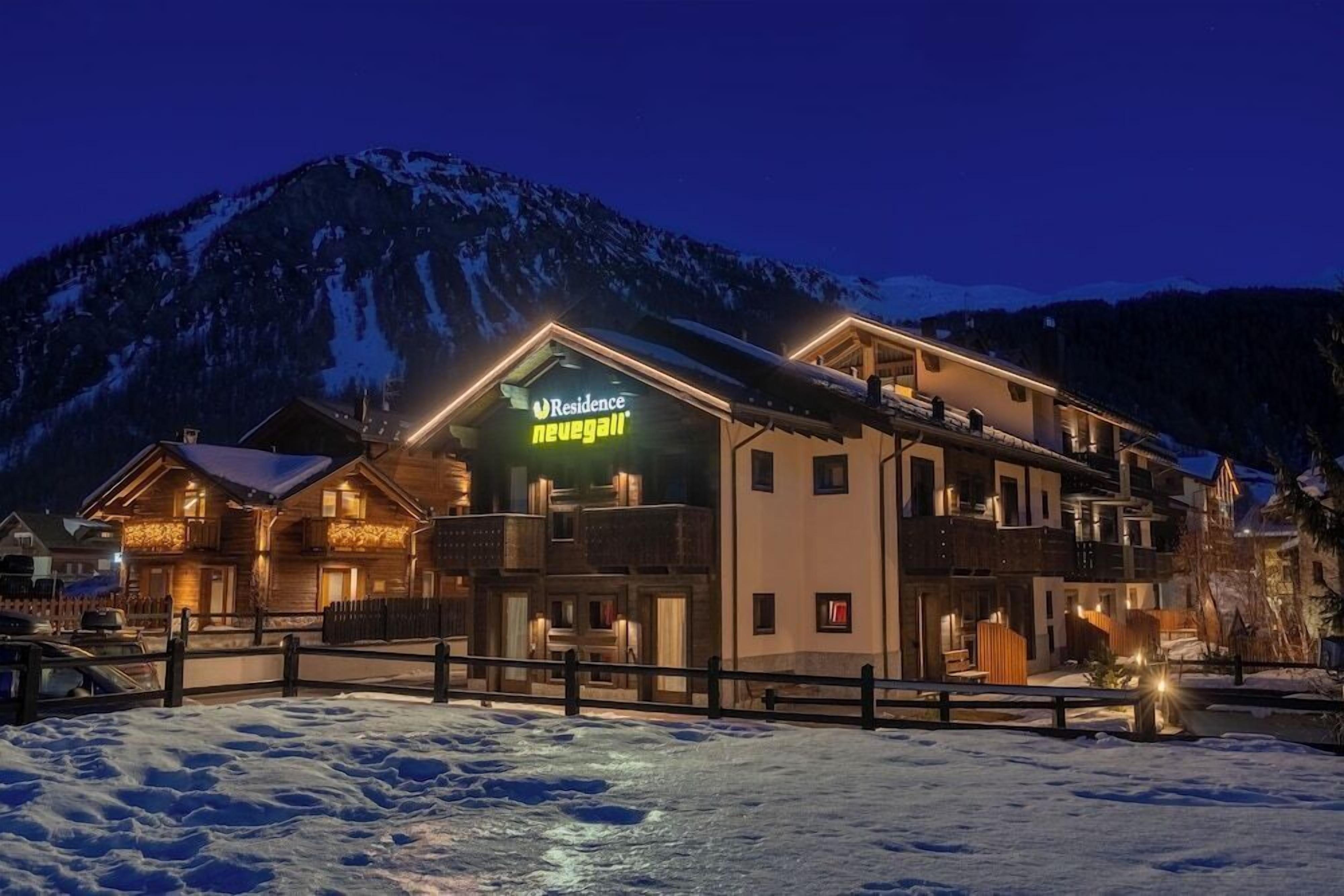 A hotel with a sign reading "Residence Neugästei" in a mountainous area at night.