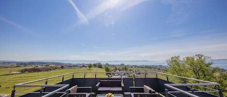 A terrace with wicker furniture and a table with fruit, overlooking a scenic landscape.