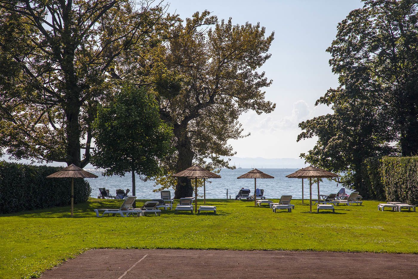 A serene outdoor seating area with umbrellas, lounge chairs, and a view of the sea.