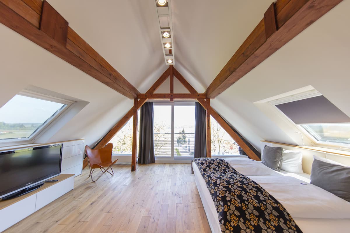 Een slaapkamer met een schuine kap, een bed, een televisie en een stoel.