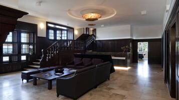 Amplia sala de estar con un sofá de color oscuro, una mesa de centro y una escalera que conduce a un nivel superior.