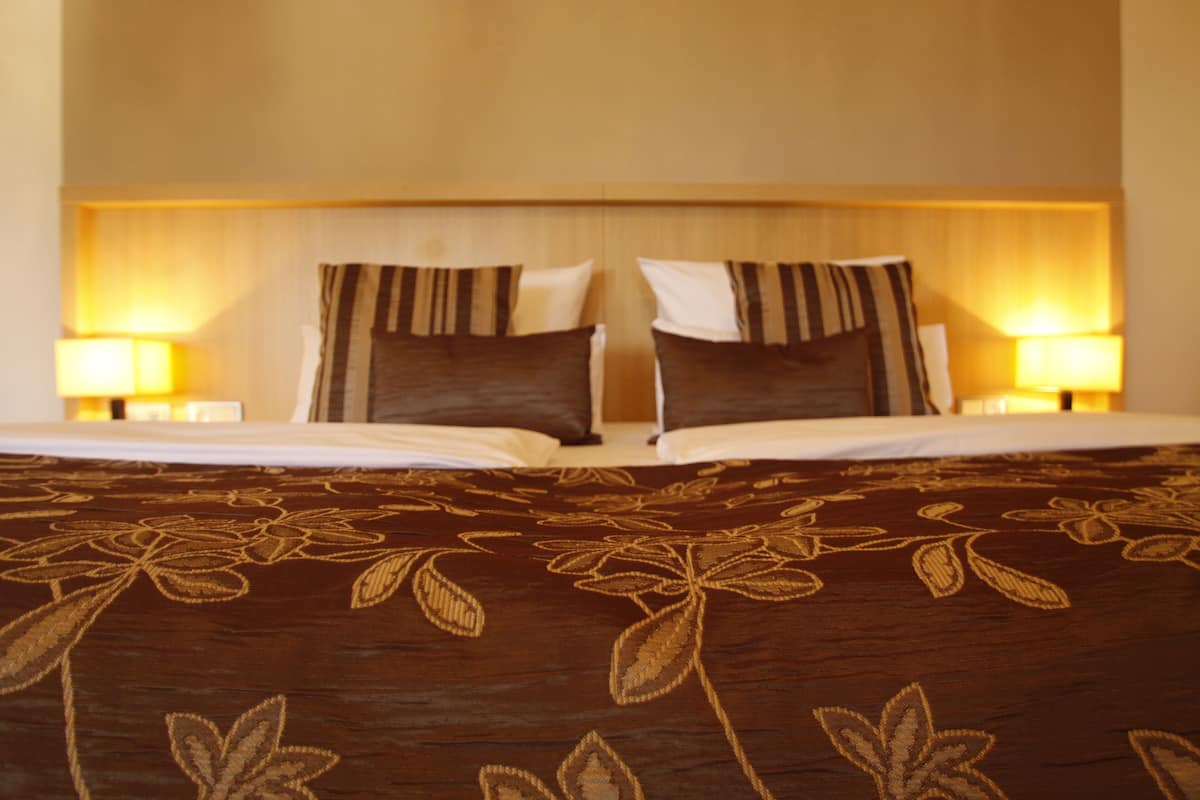 Een hotelkamer met een groot bed, twee bedlampen en een hoofdeinde met een strepenpatroon.