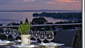 A dining table set for two with a view of a lake and distant mountains. - Bodensee Hotel Sonnenhof (Kressbronn)