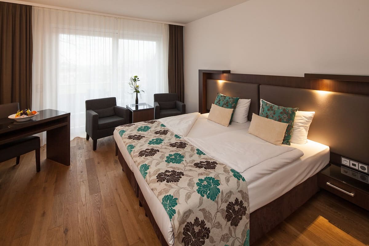 Een hotelkamer met een groot bed, een bureau en een stoel.
