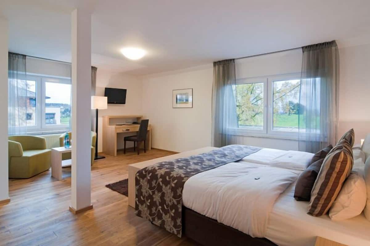 Een moderne hotelkamer met een groot bed, een bureau, een stoel en een bank.