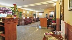 A hotel lobby with a reception desk, seating area, and a decorative plant. - Albergo Paradiso (Monte Compatri)