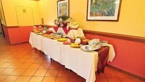 A long table with various dishes and a centerpiece, set against a yellow wall with a framed picture above it. - Albergo Paradiso (Monte Compatri)