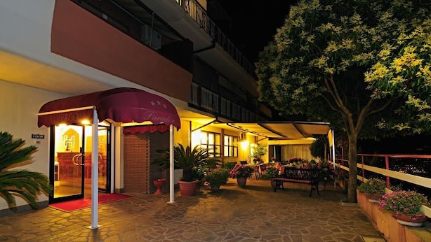 A hotel entrance with a red awning, a reception desk, and a stone-paved patio with potted plants and a bench. - Albergo Paradiso (Monte Compatri)