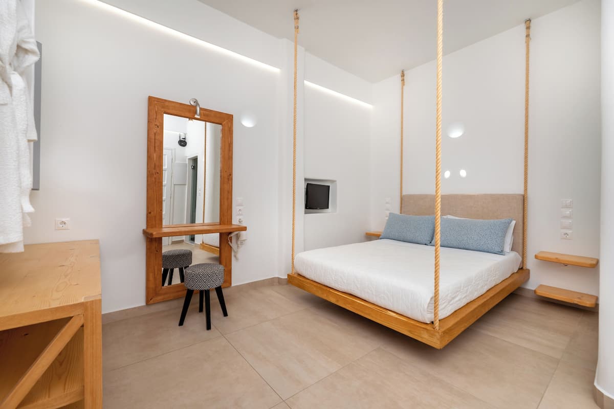 A modern bedroom with a hanging bed, a wooden desk, and a small stool.