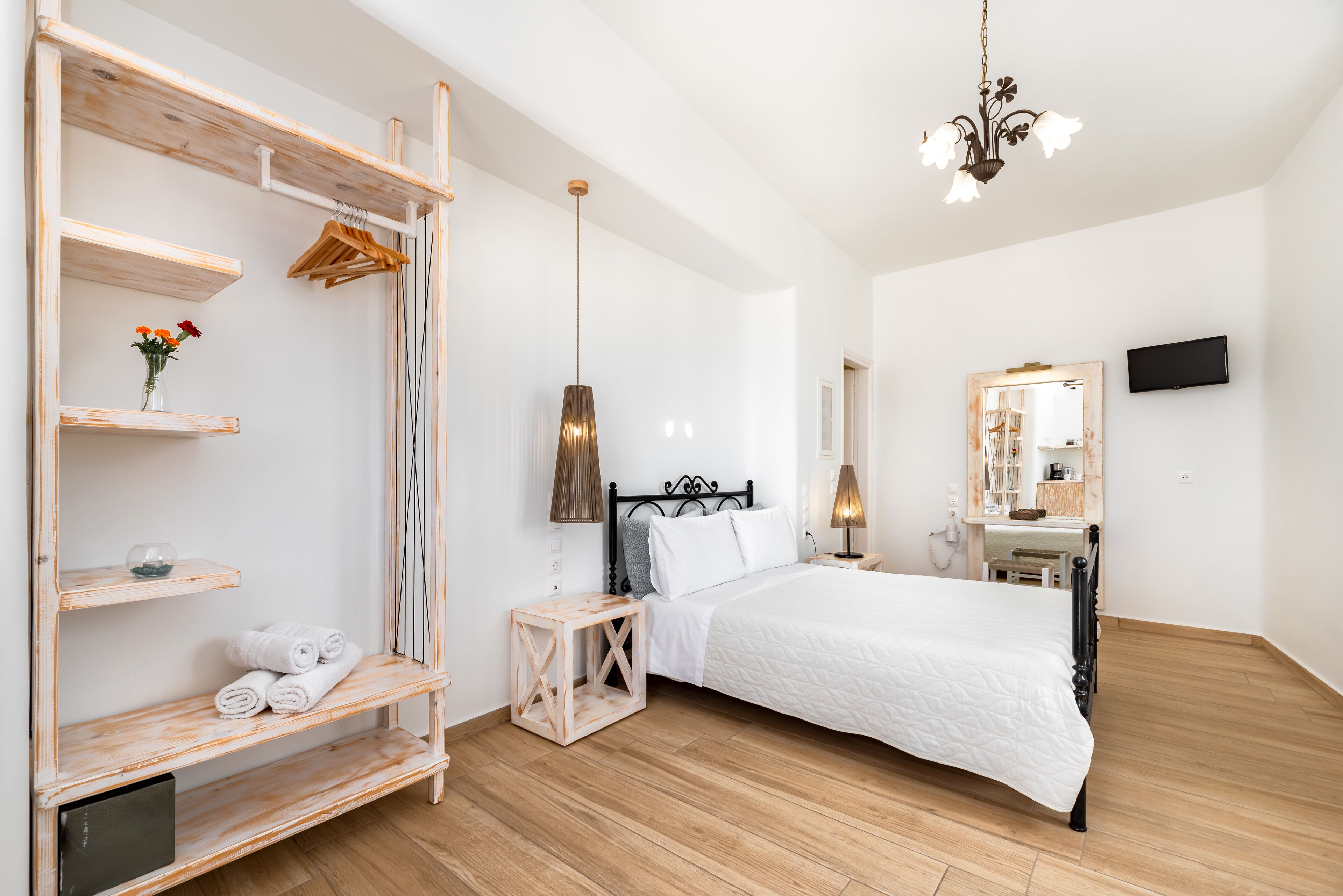 Un dormitorio con cama, estanterías de madera, un espejo y televisión.