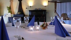 Une table à manger dressée avec des serviettes bleues, des verres à vin et une bougie.