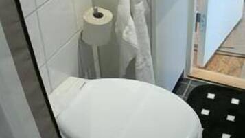 A bathroom with a white toilet, a sink, and a towel hanging on a rack.