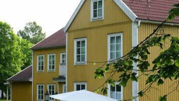 A yellow building with a red roof, multiple windows, and a white awning.