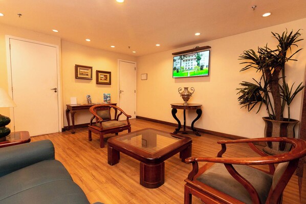 A living room with wooden furniture, a television, and a potted plant.